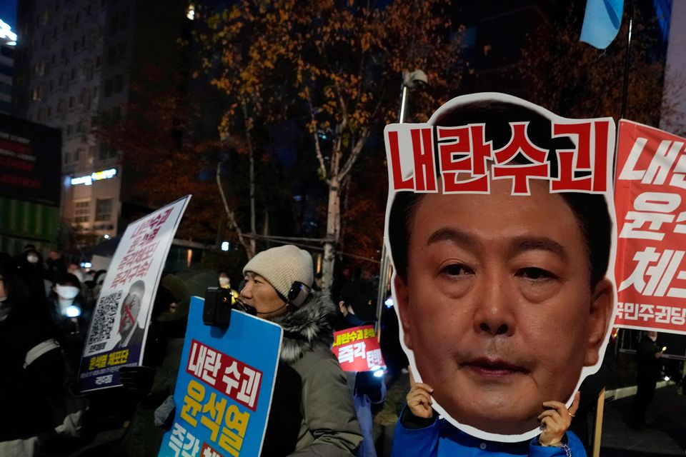 A protester wearing a mask of President Yoon Suk Yeol attends a rally demanding his impeachment outside the National Assembly in Seoul (Ahn Young-joon/AP)