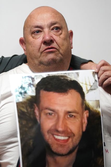 Billy, the father of John George, holds a photo of his son after returning to Belfast following the search (PA)