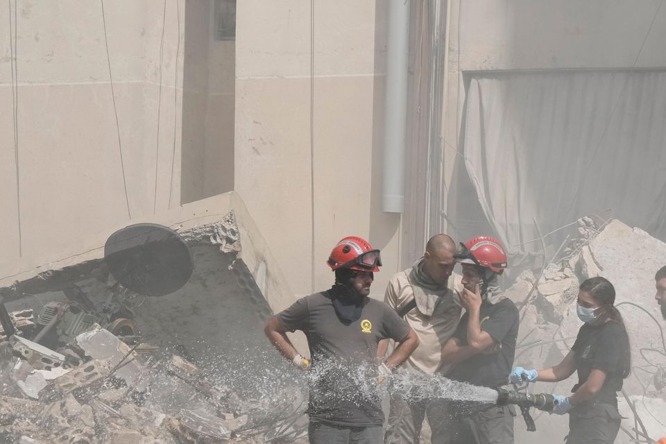 Civil defence workers extinguish a fire as smoke rises from the site of the attack (Bilal Hussein/AP)