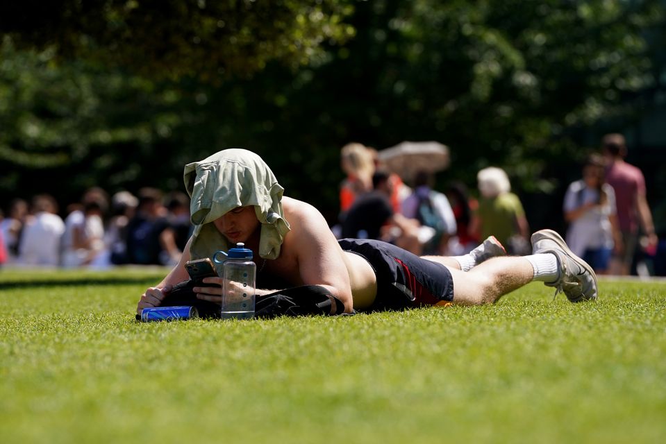 A sunbather used his T-shirt to protect his head during high temperatures in London (Lucy North/PA)