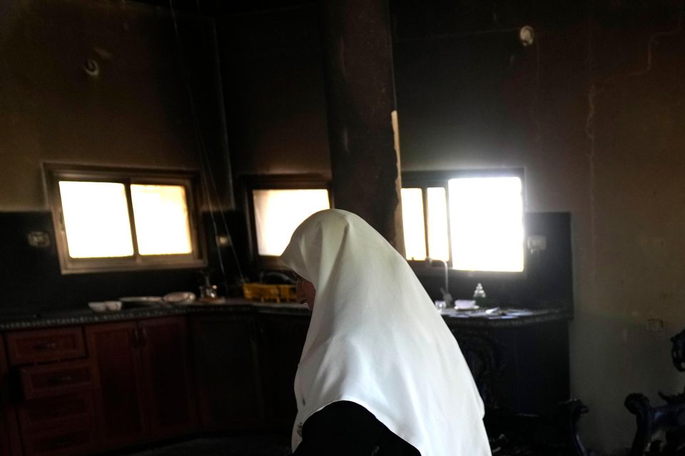 A Palestinian woman stands in her home the morning after it was torched in a rampage by Israeli settlers in the West Bank village of Jit (Nasser Nasser/AP)