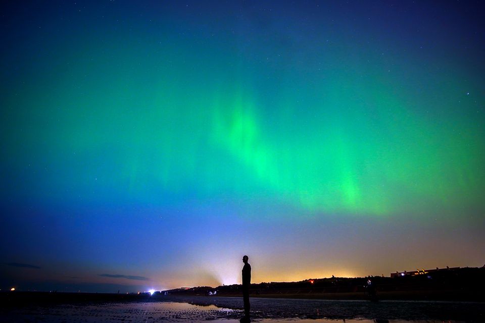 The aurora borealis, also known as the Northern Lights, glow on the horizon at Another Place by Anthony Gormley on Crosby Beach in Merseyside in May (Peter Byrne/PA)