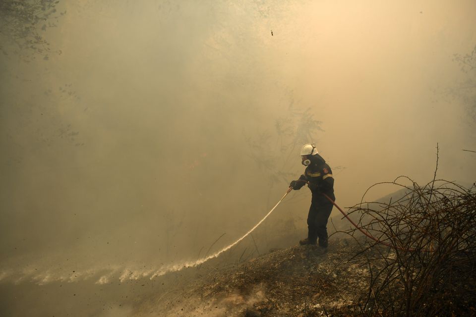 A firefighter tries to extinguish a fire in northern Athens (Michael Varaklas/AP)