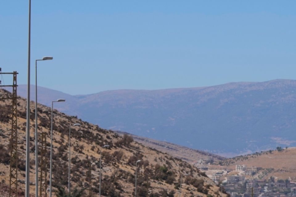 People carry their luggage as they cross into Syria on foot (Hassan Ammar/AP)