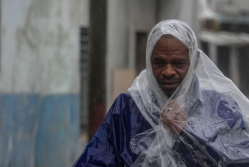 A man walks through the wind and rain (Ramon Espinosa/AP)