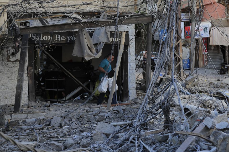 A man carries his belongings in the debris of destroyed buildings in Tyre (Mohammed Zaatari/AP)