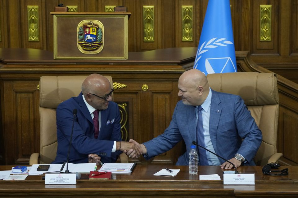 Karim Khan, chief prosecutor of the International Criminal Court, right, shakes hands with National Assembly President Jorge Rodriguez during a meeting at the National Assembly (AP/Ariana Cubillos)