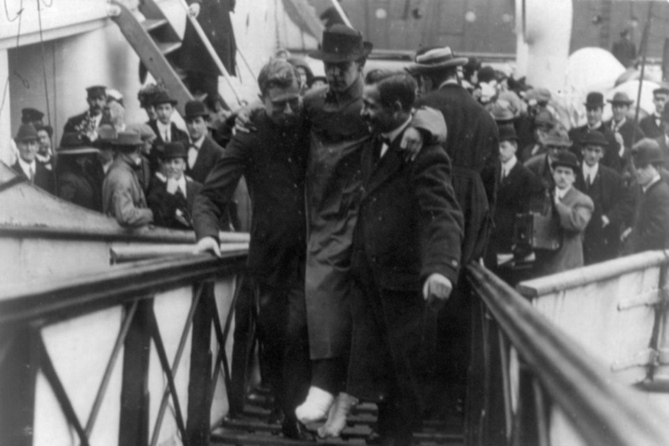 In this 1912 photo made available by the Library of Congress, Harold Bride, surviving wireless operator of the Titanic, with feet bandaged, is carried up the ramp of a ship.