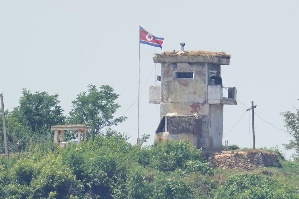 A North Korean soldier stands at the North’s military guard post as a North Korean flag flutters in the wind, seen from Paju, South Korea (AP)