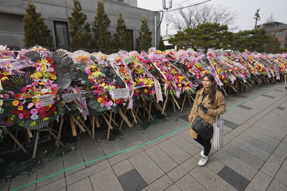 A woman passes wreaths sent by supporters of impeached South Korean President Yoon Suk Yeol outside the Constitutional Court in Seoul (Lee Jin-man/AP)