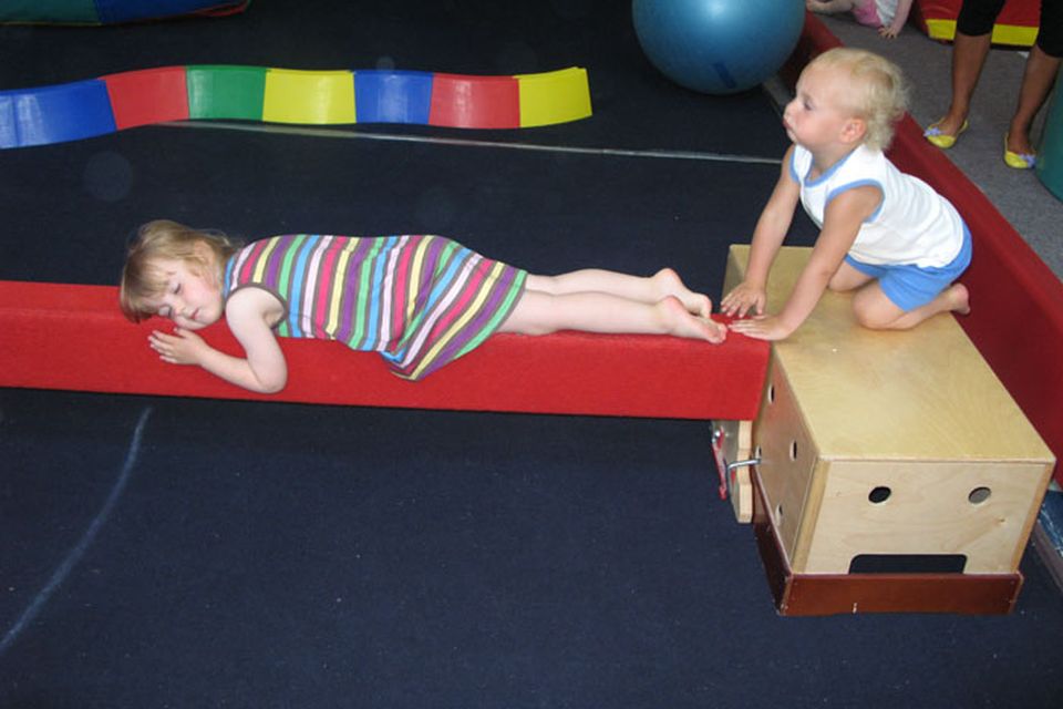 Oliver (right) waits for Emily to waken up as she pretends to sleep on one of the gym beams