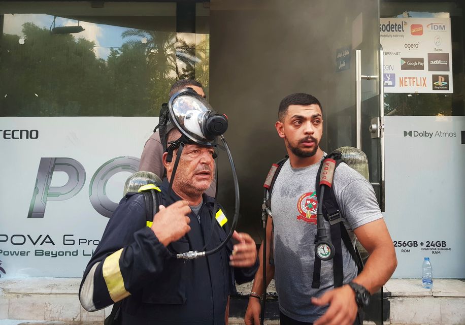 Firefighters stand outside a damaged mobile shop after what is believed to be the result of a walkie-talkies exploding inside it, in the southern port city of Sidon, Lebanon, Wednesday, Sept. 18, 2024 (AP Photo/Mohammed Zaatari)