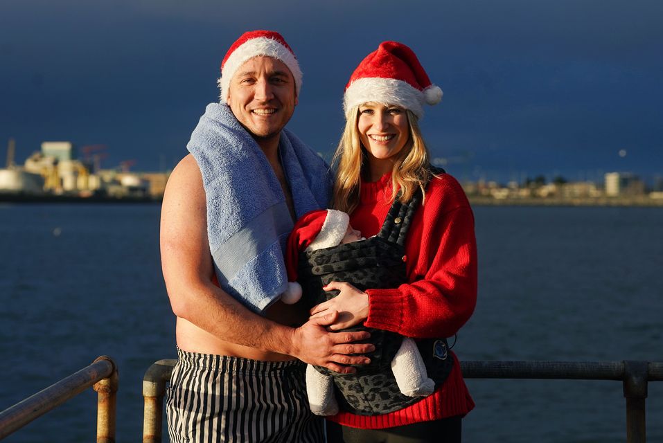 Sean Mulligan (left) and Jill Owens ensured their 10-week-old daughter Maisie Mulligan was well wrapped up to watch her father swim at Clontarf (Brian Lawless/PA)