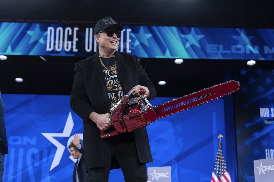 Elon Musk hold a chainsaw as he arrives to speak (Jose Luis Magana/AP)