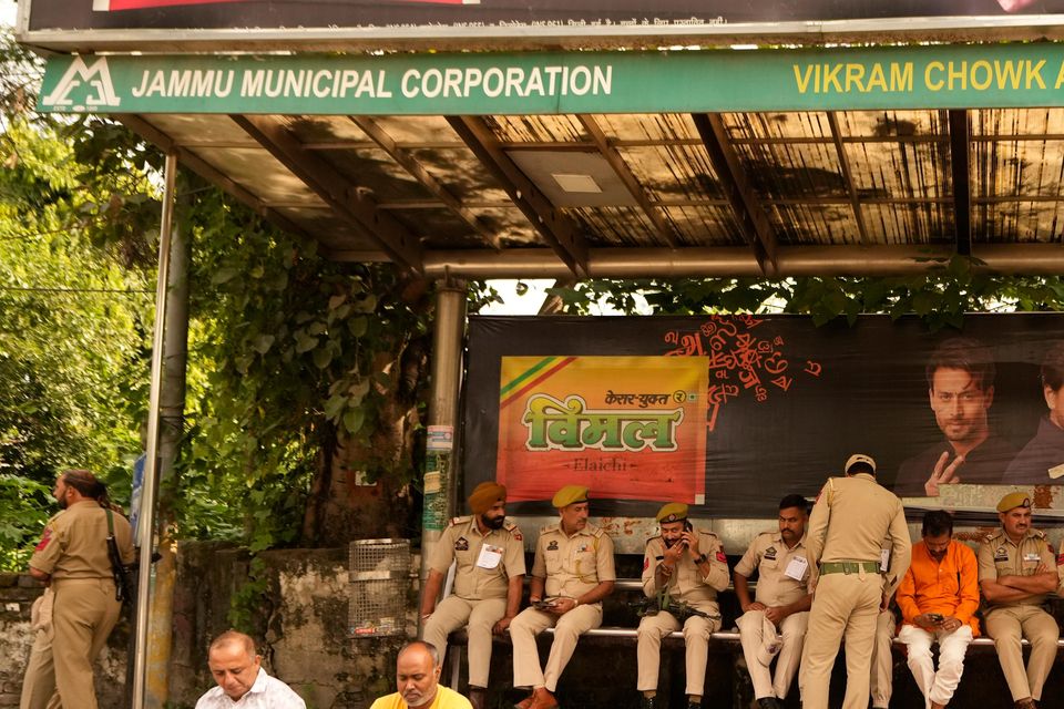 Security workers rest under a passenger shed outside a counting centre in Jammu, India (Channi Anand/AP)