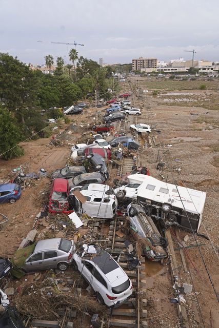 Vehicles are strewn across railway tracks after floods on the outskirts of Valencia (Alberto Saiz/AP)