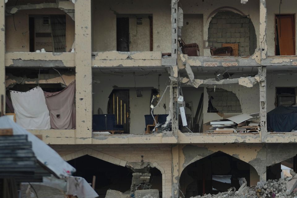 Palestinians walk past destroyed buildings in Khan Younis, Gaza Strip (Abdel Kareem Hana/AP)