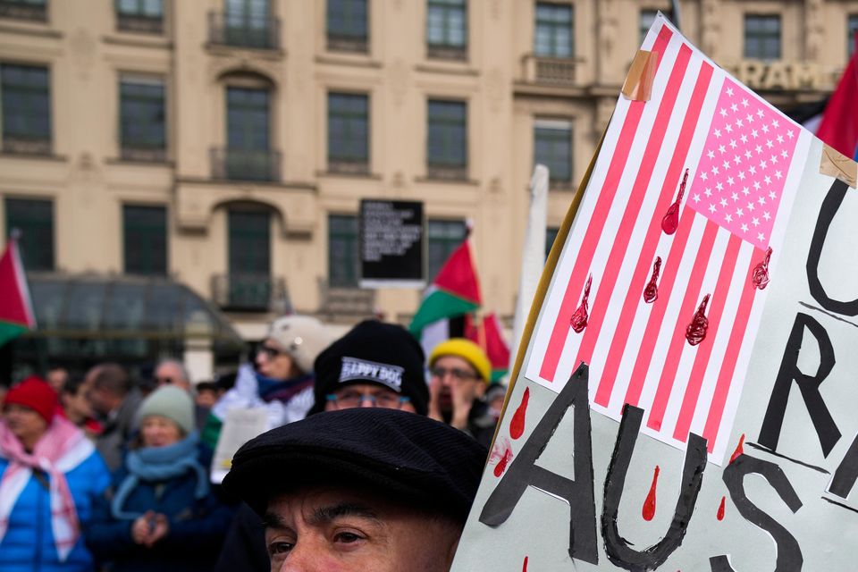 A man holds a poster reading USA: Out of Europe, during a protest against the Munich Security Conference (Ebrahim Noroozi/AP)