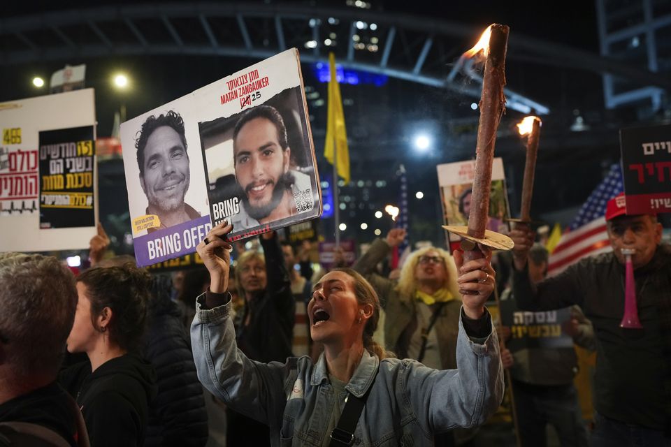 Demonstrators in Tel Aviv, Israel, hold torches during a protest calling for the immediate release of the hostages held in the Gaza Strip by Hamas (Ohad Zwigenberg/AP)