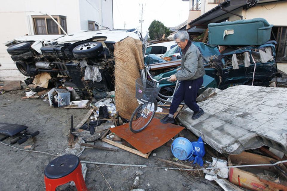 A resident of the seaside town of Yotsukura, northern Japan, carries his bike through debris Monday, March 14, 2011, three days after a giant quake and tsunami struck the country's northeastern coast. (AP Photo/Mark Baker)
