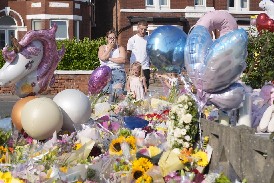 People look at floral tributes on Maple Street, Southport (Danny Lawson/PA)