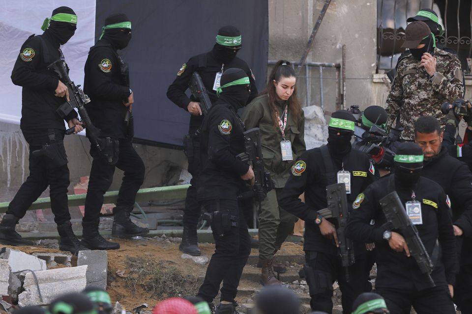 Israeli soldier Agam Berger walks next to masked Islamic Jihad militants as she is handed over to the Red Cross at the Jabalya refugee camp in Gaza City (Mohammed Hajjar/AP)