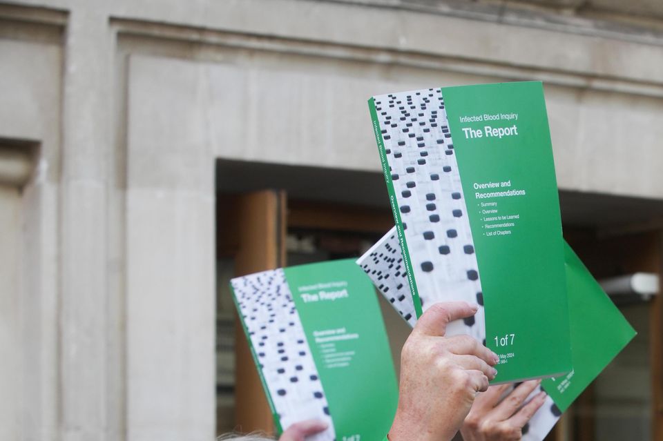 People hold up copies of the Infected Blood Inquiry report outside Central Hall in Westminster, London (Jeff Moore/PA)