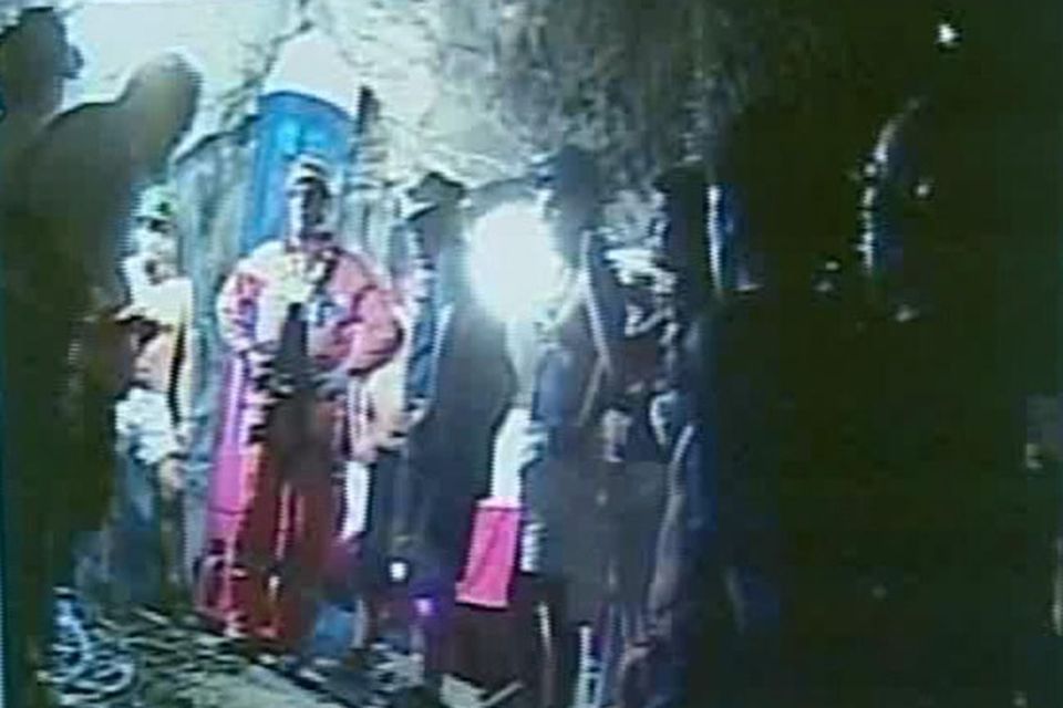 In this screen grab taken from video, rescuer Manuel Gonzalez Pavez, second left, speaks to the 33 trapped miners after being lowered into the mine near Copiapo, Chile.(AP Photo)
