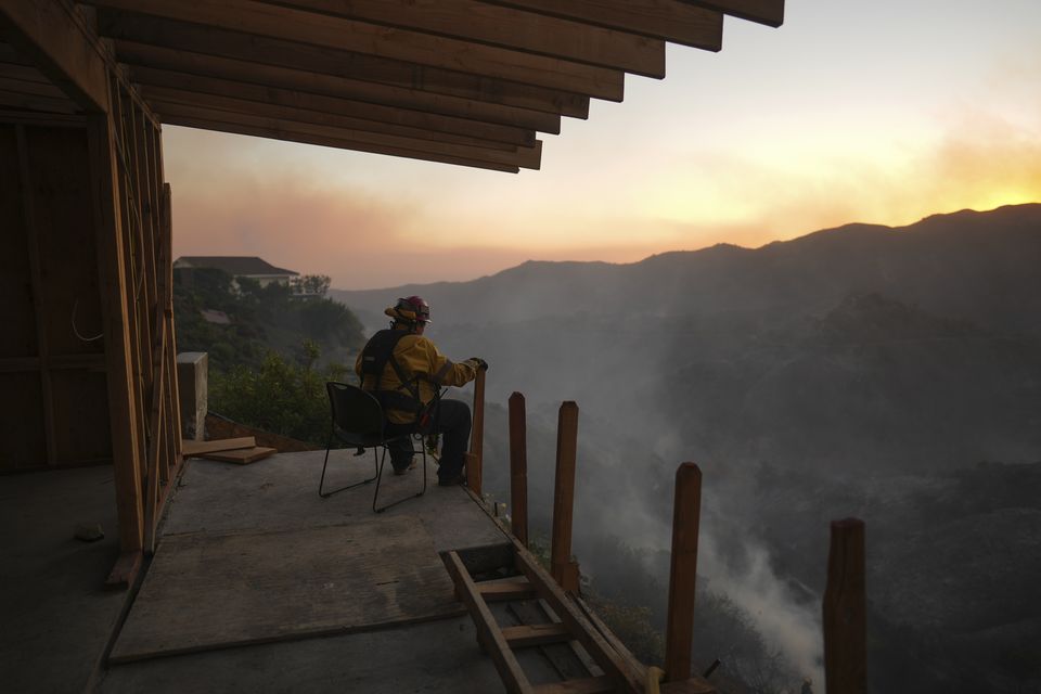 A firefighter rests as crews battle the Palisades Fire in Mandeville Canyon (Eric Thayer/AP)