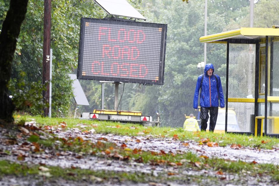 A man walks past a flood sign in Liverpool amid heavy rain in parts of the country (Peter Byrne/PA)