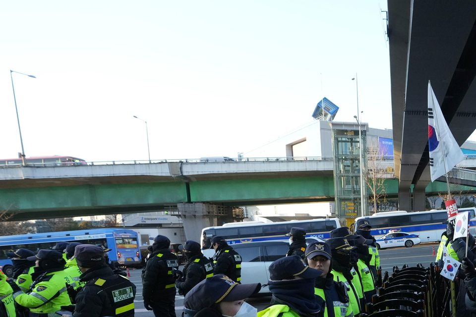 Supporters of impeached South Korean President Yoon Suk Yeol stage a rally to oppose a court having issued a warrant to detain him as police officers stand guard (Lee Jin-man/AP)