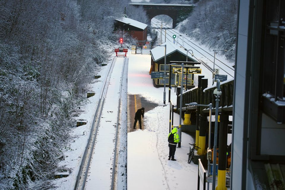 A worker clears snow from the platform at Hunt’s Cross station in Liverpool (Peter Byrne/PA)