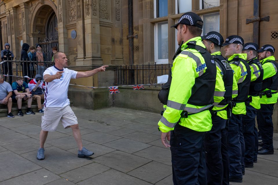 Roger Haywood stands in front of a line of police (Michael Holmes/PA)