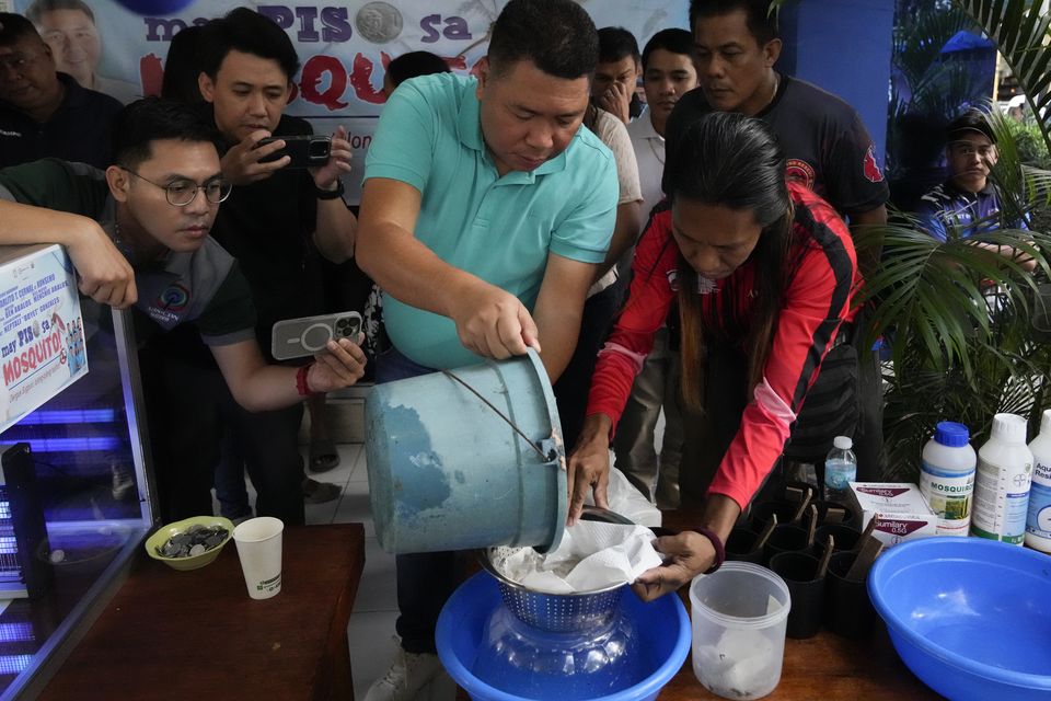 Addition Hills village chief Carlito Cernal, centre, decided to take action after cases of dengue fever in the area surged (Aaron Favila/AP)