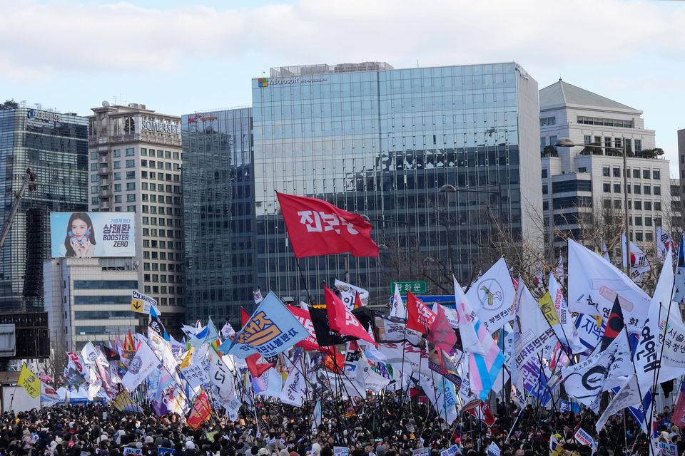 Protesters carry flags during a rally demanding the indictment of impeached South Korean President Yoon Suk Yeol (Ahn Young-joon/AP)