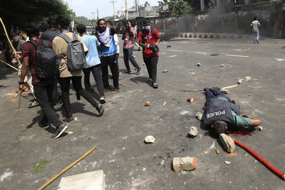 An injured policeman lies on a street during clashes with students in Dhaka, Bangladesh (Rajib Dhar/AP)