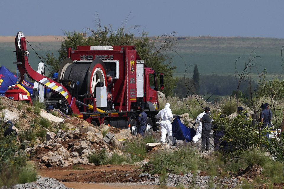 Forensic service workers carry remains in blue body bags during an operation to rescue miners from below ground in Stilfontein (Themba Hadebe/AP)