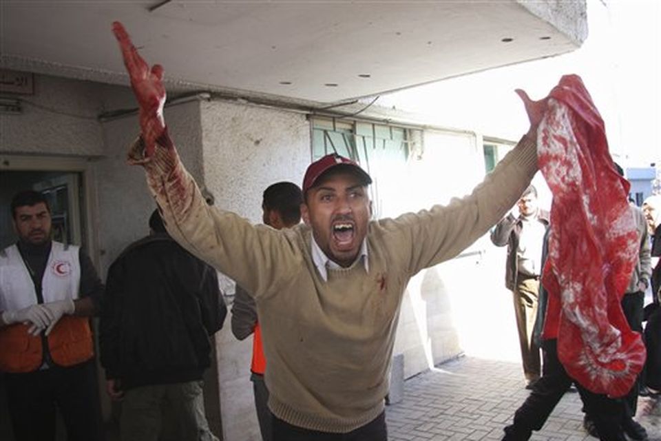 A Palestinian man reacts as he holds a blood stained sheet at the entrance to Shifa Hospital in Gaza City, Thursday, Jan. 15, 2009. Israeli forces shelled the United Nations headquarters in the Gaza Strip on Thursday, setting the compound on fire as U.N. chief Ban Ki-moon was in the area on a mission to end Israel's devastating offensive against the territory's Hamas rulers. (AP Photo/Thaer Al-Hasani)