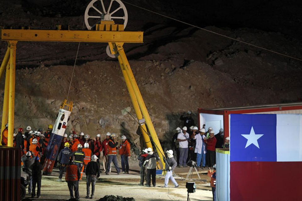 Mining Minister Laurence Golborne and rescue chief Andre Sougarrete, right, hold hands as rescue worker Manuel Gonzalez Paves is lowered in the capsule into the mine where miners are trapped to begin the rescue  at the San Jose Mine near Copiapo, Chile.(AP Photo/Roberto Candia)