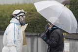 thumbnail: An official wearing a protective suit helps usher people through a radiation emergency scanning center in Koriyama, Japan, Tuesday, March 15, 2011, four days after a giant quake and tsunami struck the country's northeastern coast. (AP Photo/Mark Baker)