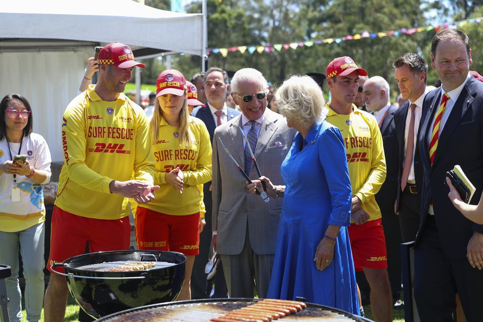 Click go the tongs, as King Charles III and Queen Camilla laugh as they turn some sausages during the community barbeque (Toby Mellville/PA)