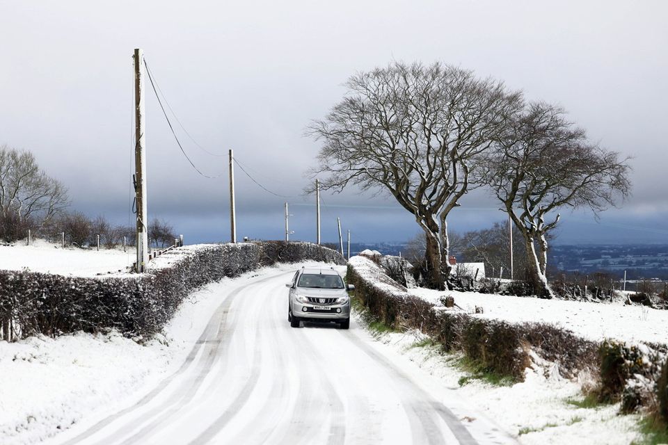 A car struggles to makes its way along the snow-covered Crosskennan Road between Antrim and Kells in Co Antrim today (Pic: Stephen Davison / Pacemaker Press)