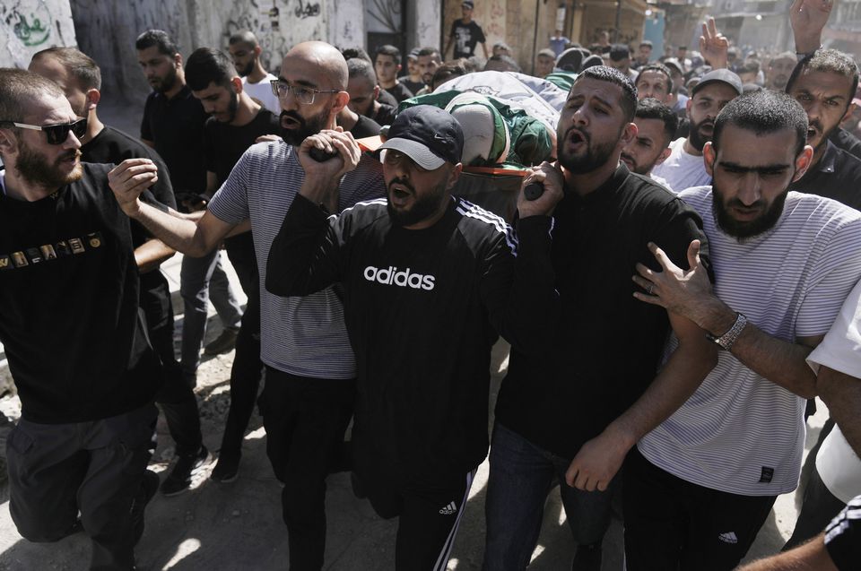 Mourners carry the body of militant Haitham Balidi, draped in the Qassam Brigade flag of the Hamas militant group’s military wing, in Tulkarem refugee camp in the West Bank (Majdi Mohammed/AP)