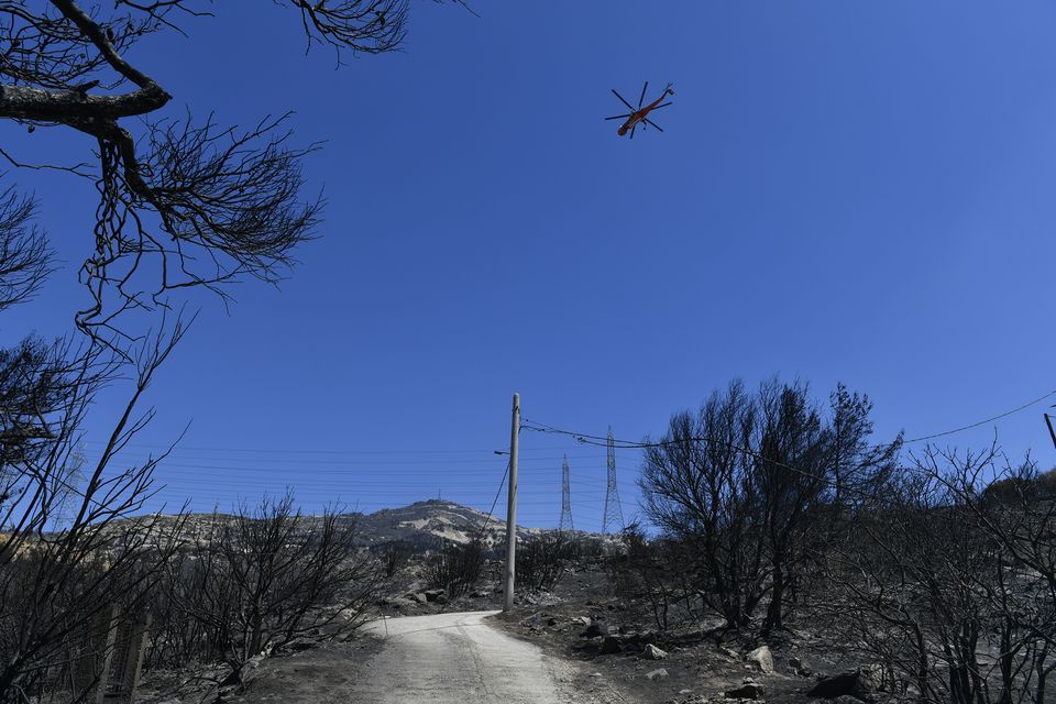 A firefighting helicopter flies in the Nea Penteli suburb of Athens (Michael Varaklas/AP/PA)