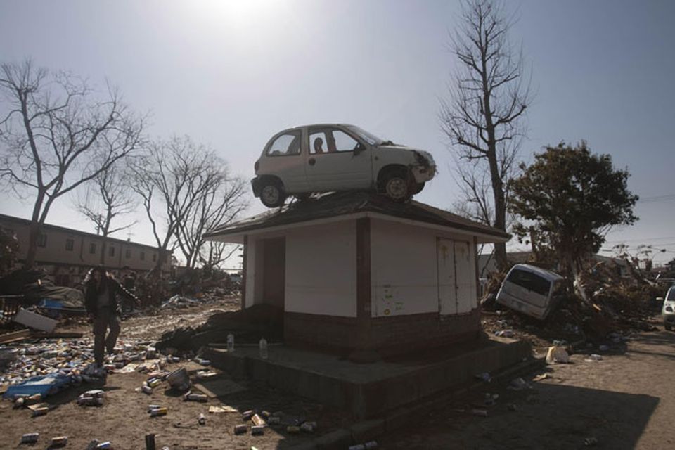 A car sits on top of a small building in a destroyed neighborhood in Sendai, Japan, on Sunday, March 13, 2011 after it was washed into the area by the tsunami that hit northeastern Japan. AP Photo/David Guttenfelder)