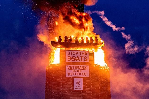 A controversial bonfire topped with an effigy of a migrant boat in Co Tyrone has been lit.