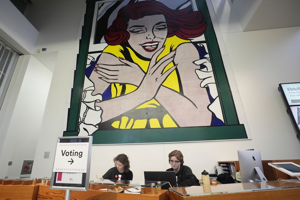 Event assistants Katie Papador, left, and Maddy Wittmers-Grave sit at the entrance of a polling location at the Weisman Art Museum in Minneapolis (Abbie Parr/AP)