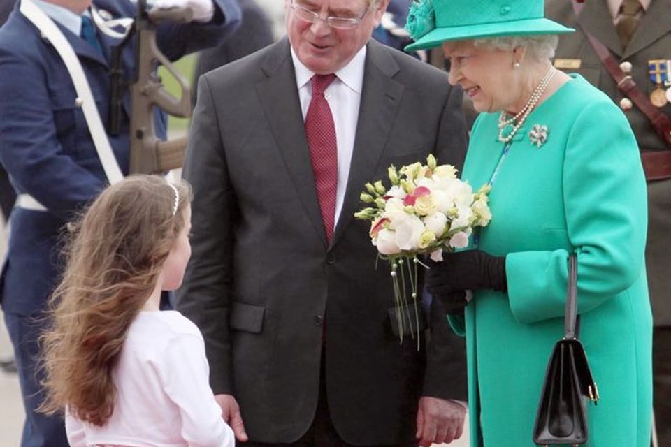 Queen Elizabeth II holds a posy of flowers given to her by eight-year-old Rachel Fox after she was greeted by Tanaiste Eamon Gilmore upon arrival at Casement Aerodrome, Baldonnel
