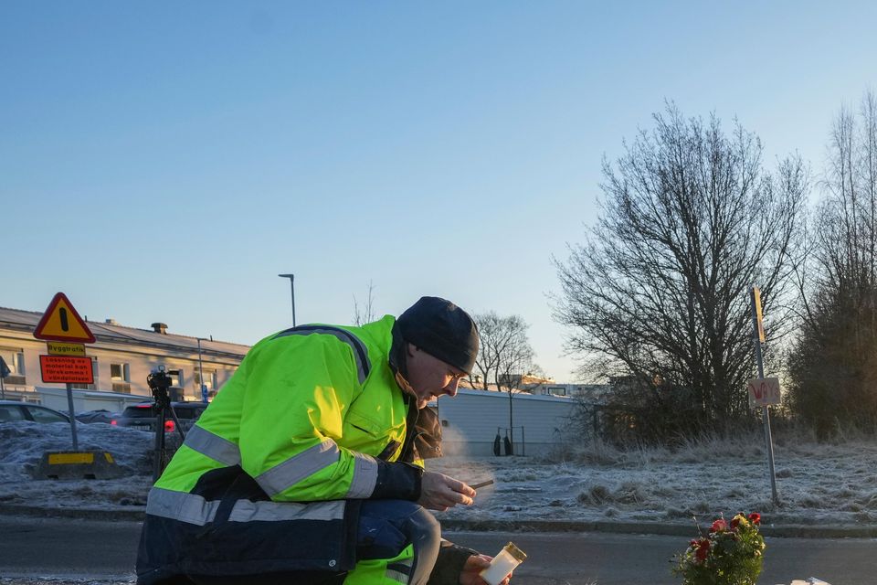 A man lights a candle at a makeshift memorial near the scene of a shooting at an adult education centre (Sergei Grits/AP)