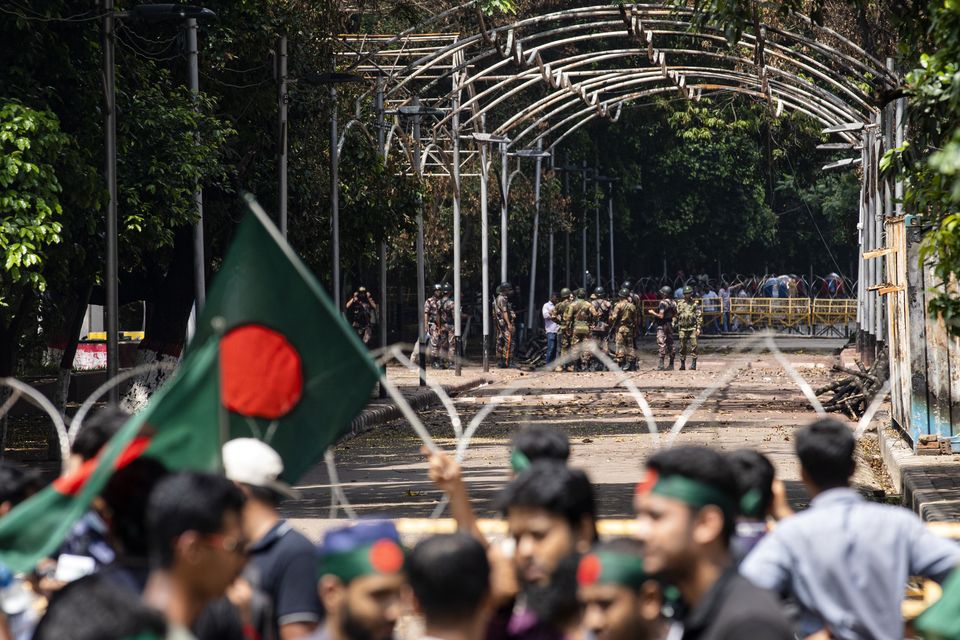 Military and paramilitary personnel stand guard as protesters block the road in front of the former residence of Sheikh Mujibur Rahman (Rajib Dhar/AP/PA)